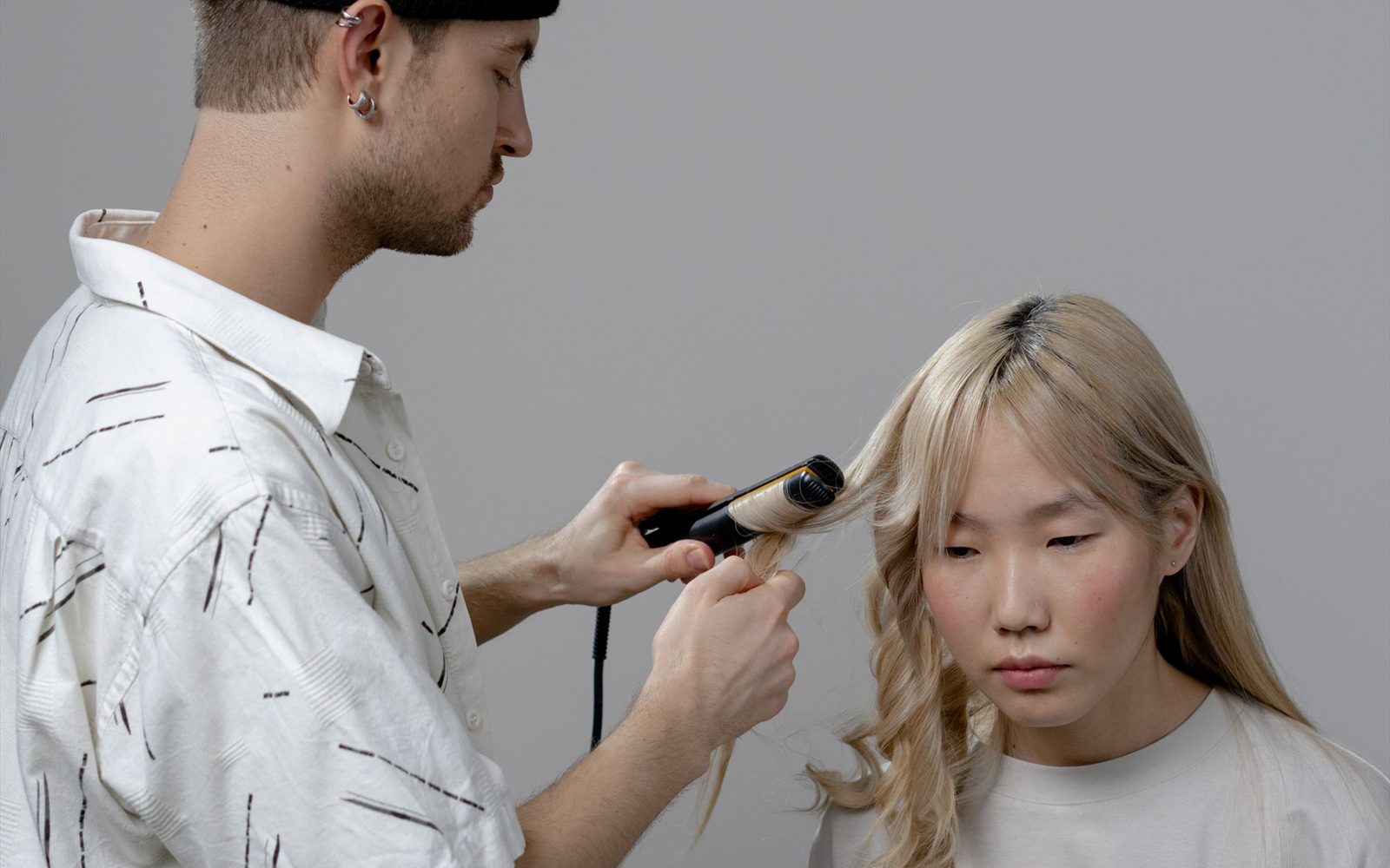 Hairstylist blow-drying a client's hair at a styling station