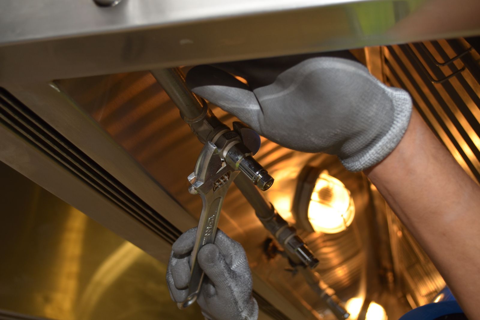 Drainage engineer tightening a pipe joint with an adjustable wrench