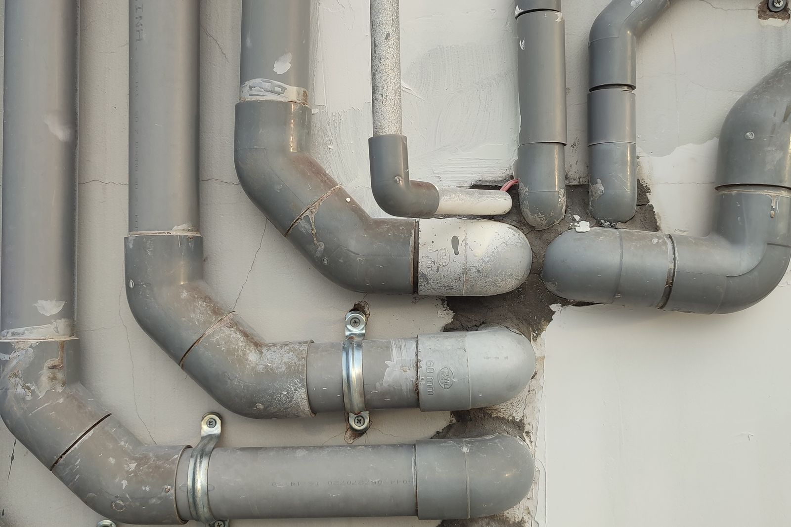 Grey PVC waste and drainage pipework running along a wall
