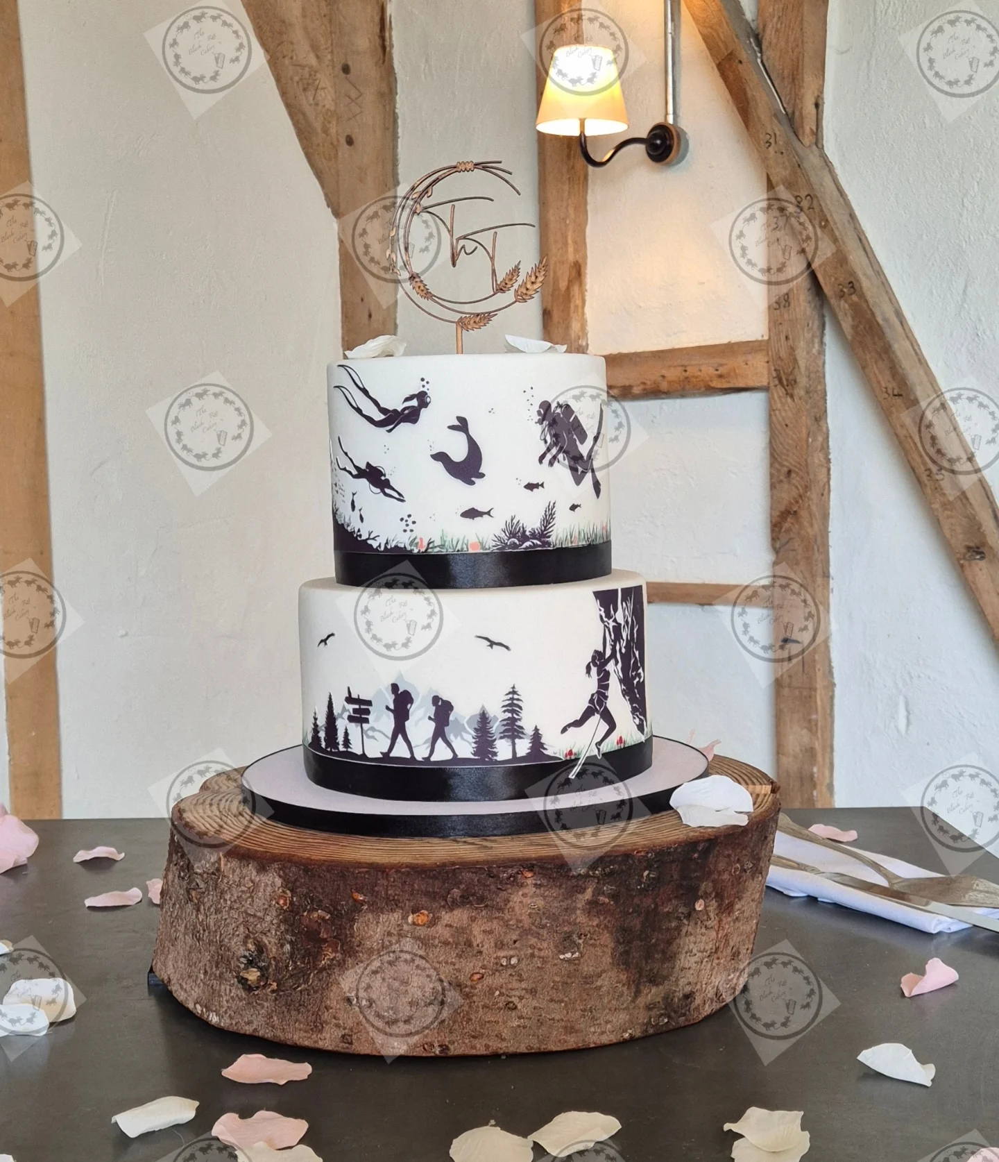 Hand-painted two-tier wedding cake by The Black Rat Cakery, decorated with fine-line illustrations of scuba divers and mountain hikers in navy on ivory fondant