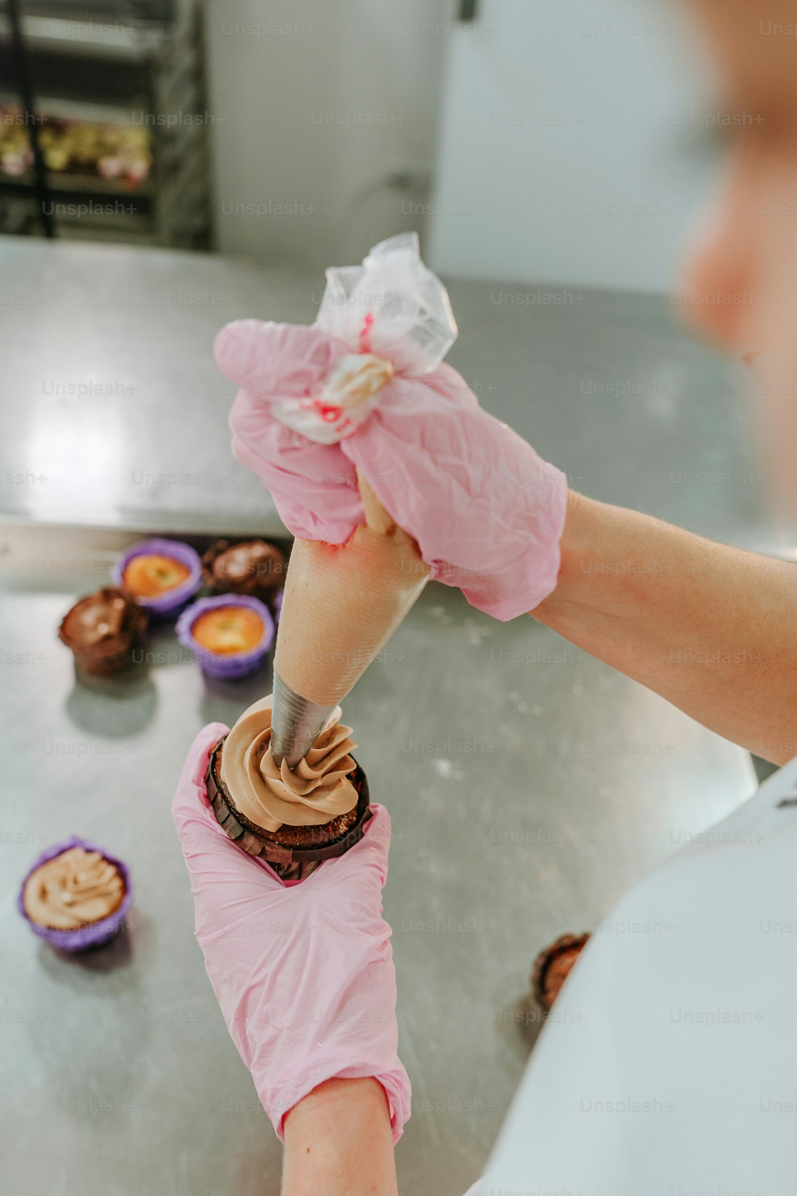 Close-up of hands piping buttercream onto a cake during a decorating class