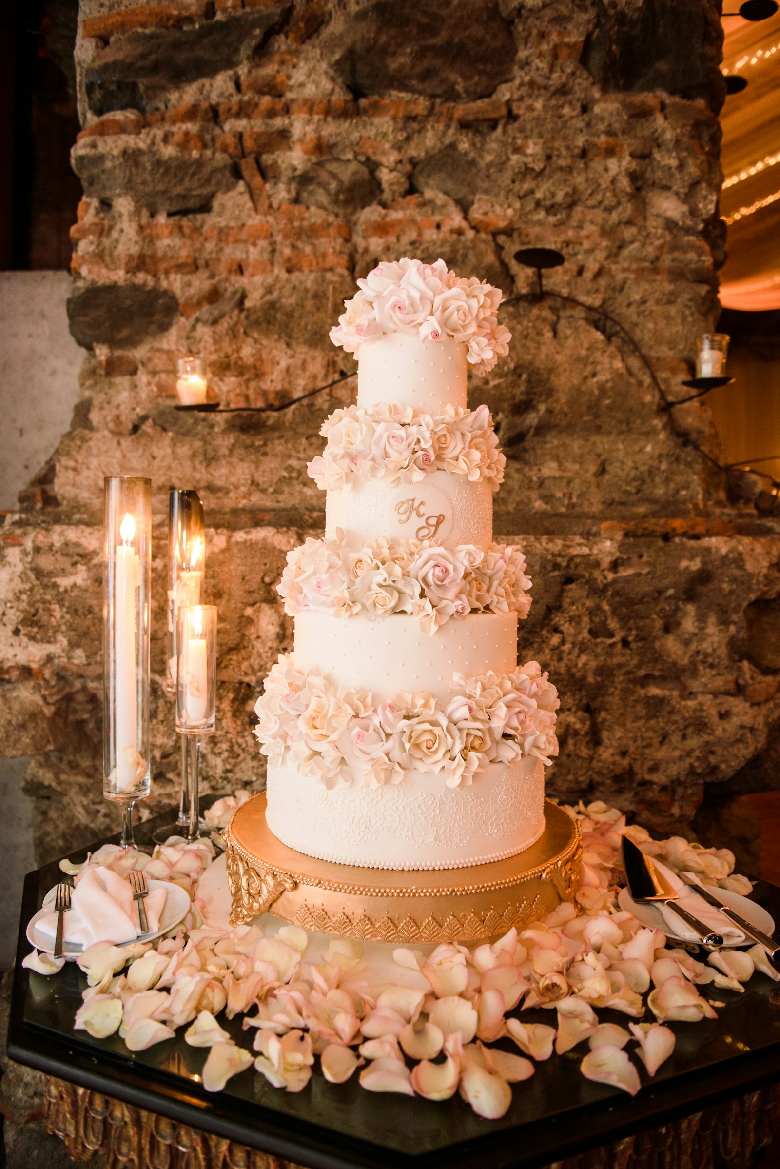 Elegant four-tier white wedding cake finished with delicate cream piping and gold detailing