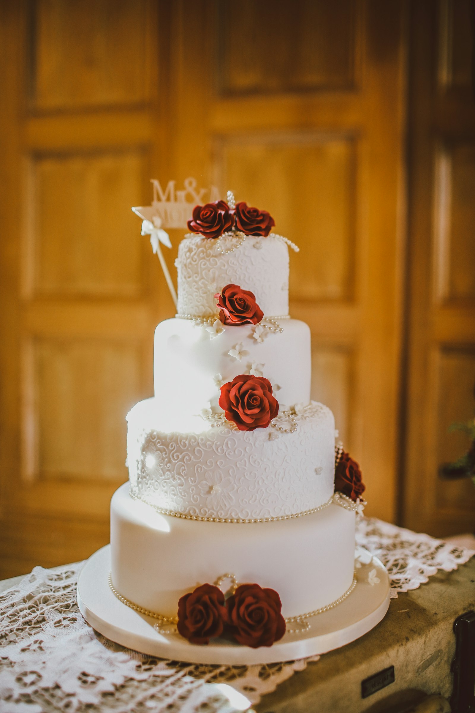 White four-tiered fondant wedding cake decorated with delicate floral details
