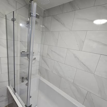 Marble-tiled bathroom with bath, glass shower screen and rainfall shower