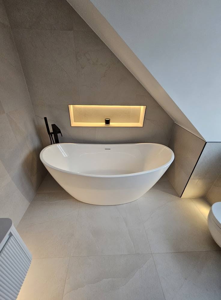 Freestanding bath beneath a sloped ceiling with LED-lit alcove