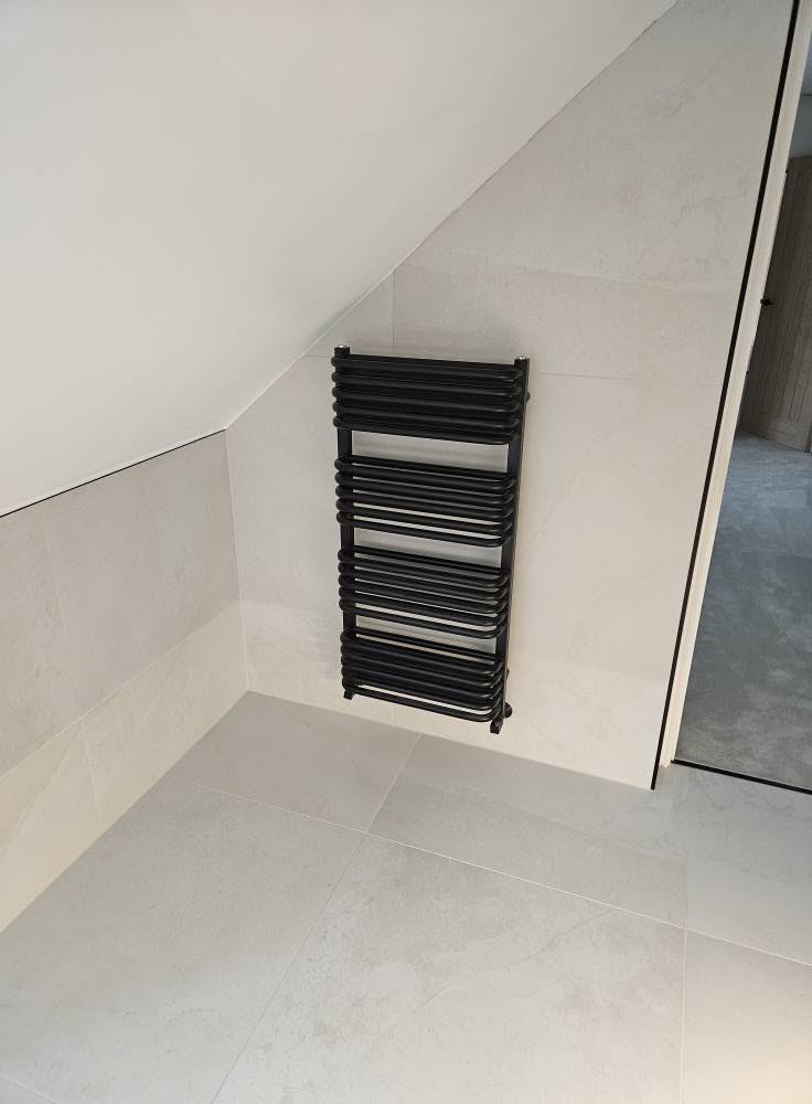 Matt black designer towel radiator on a porcelain-tiled wall