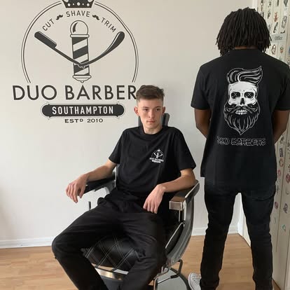 Duo Barbers clients in front of the shop's Est. 2010 wall signage, Southampton