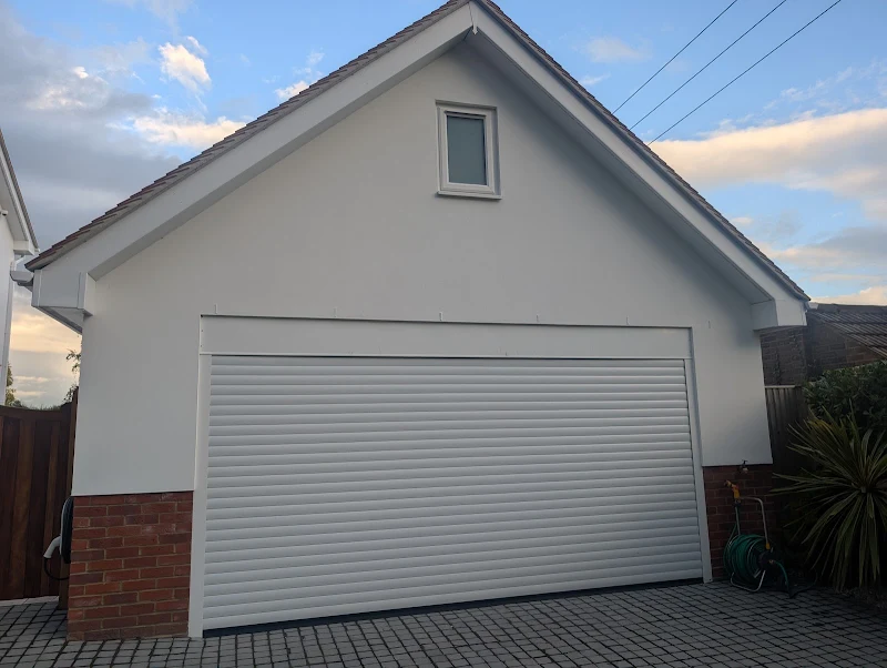 Freshly painted white render on a garage exterior with brick base