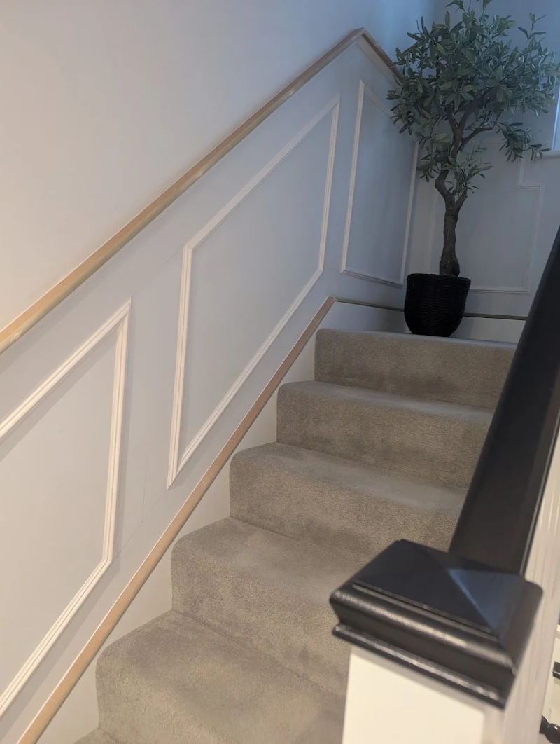 Painted staircase with wall panelling leading to a landing