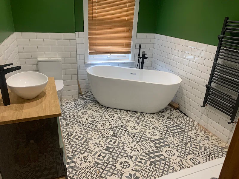 Finished bathroom refit with freestanding bath, patterned floor tiles and black towel radiator