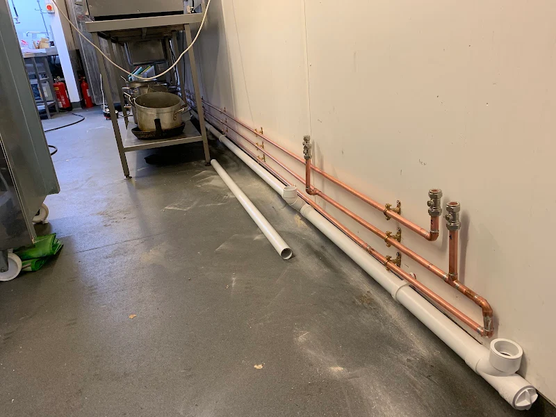 New copper supply runs and waste pipework installed along a commercial kitchen wall