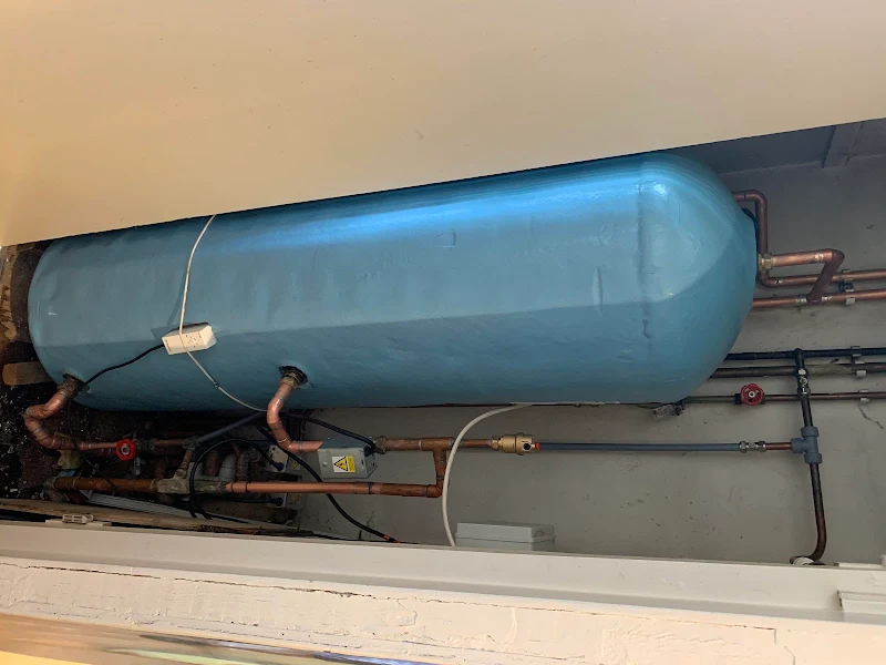 Hot water cylinder installed with neat copper pipework in an airing cupboard