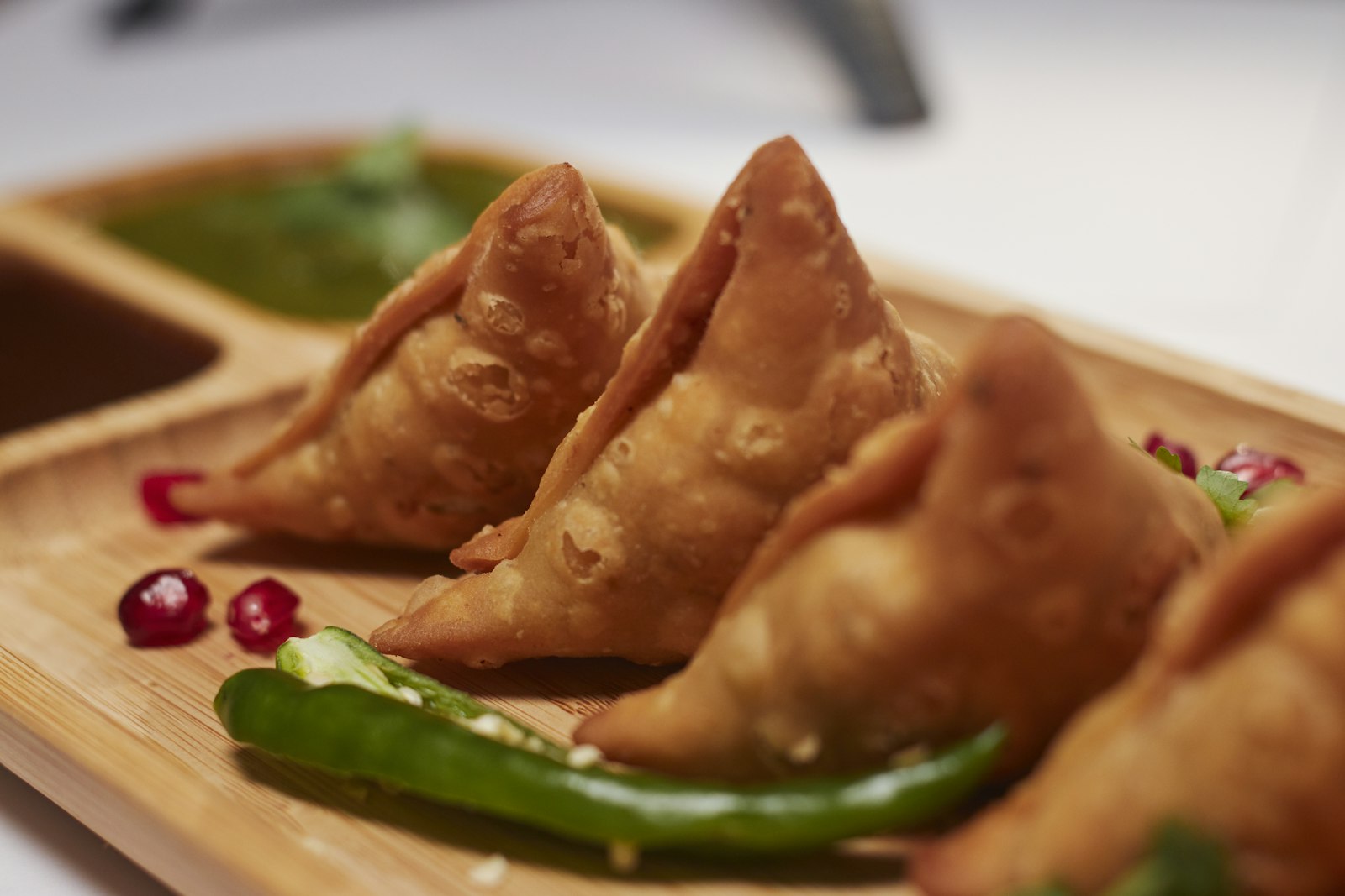 Golden fried samosas on a serving plate