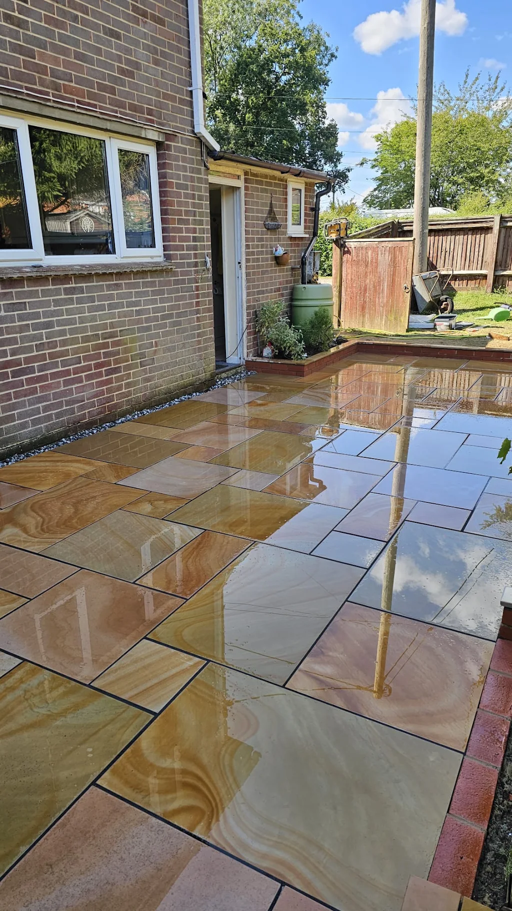 Freshly laid sandstone patio beside a conservatory, part of a Quest Landscapes project