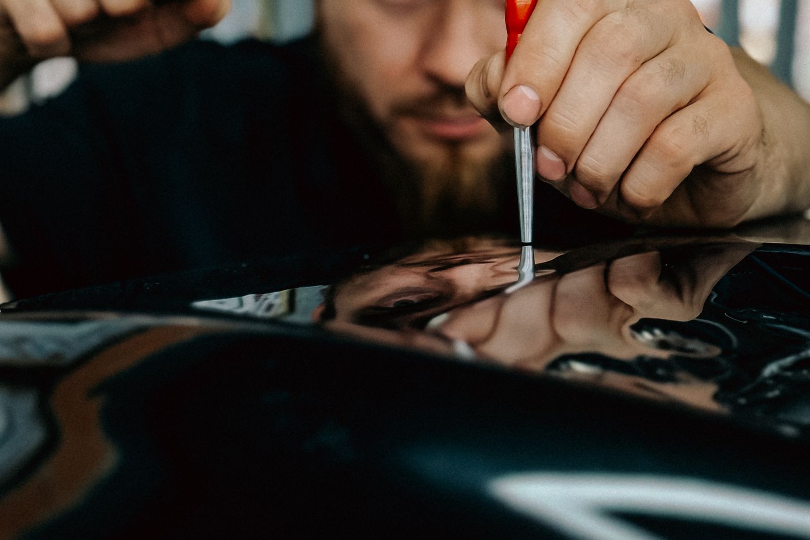 Technician working a dent out of a car panel by hand