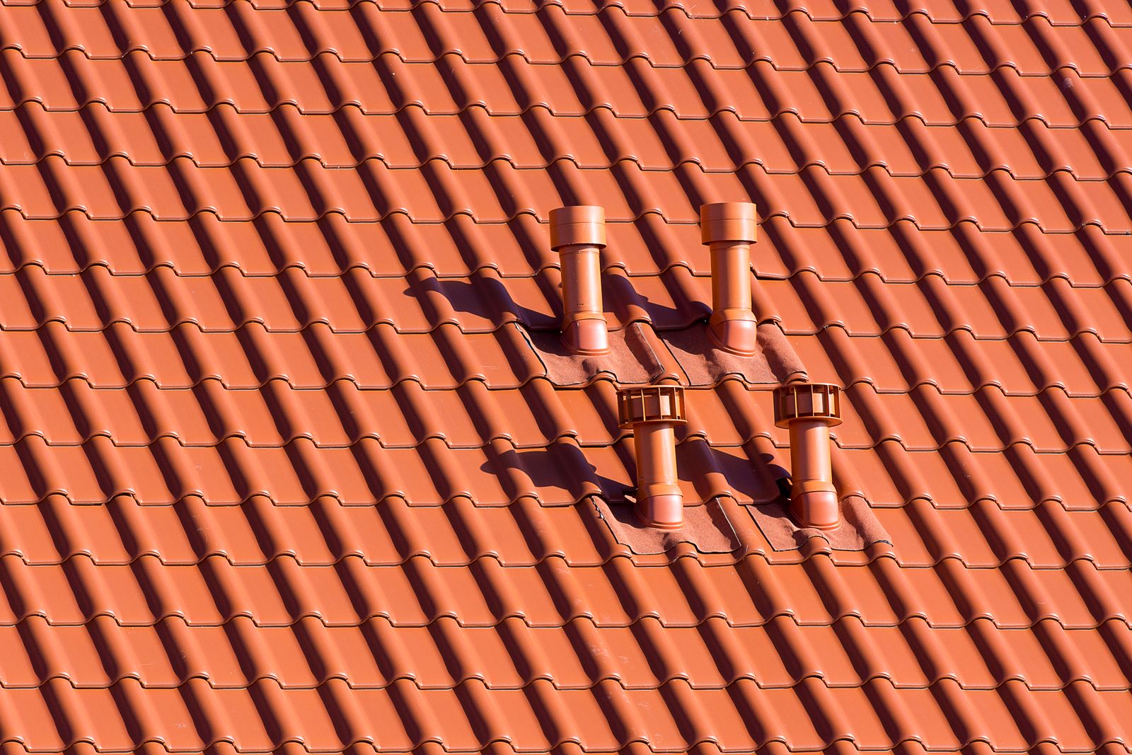 Rows of red-tiled pitched rooftops with brick chimneys