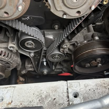 Timing belt and pulley system exposed during an engine bay repair