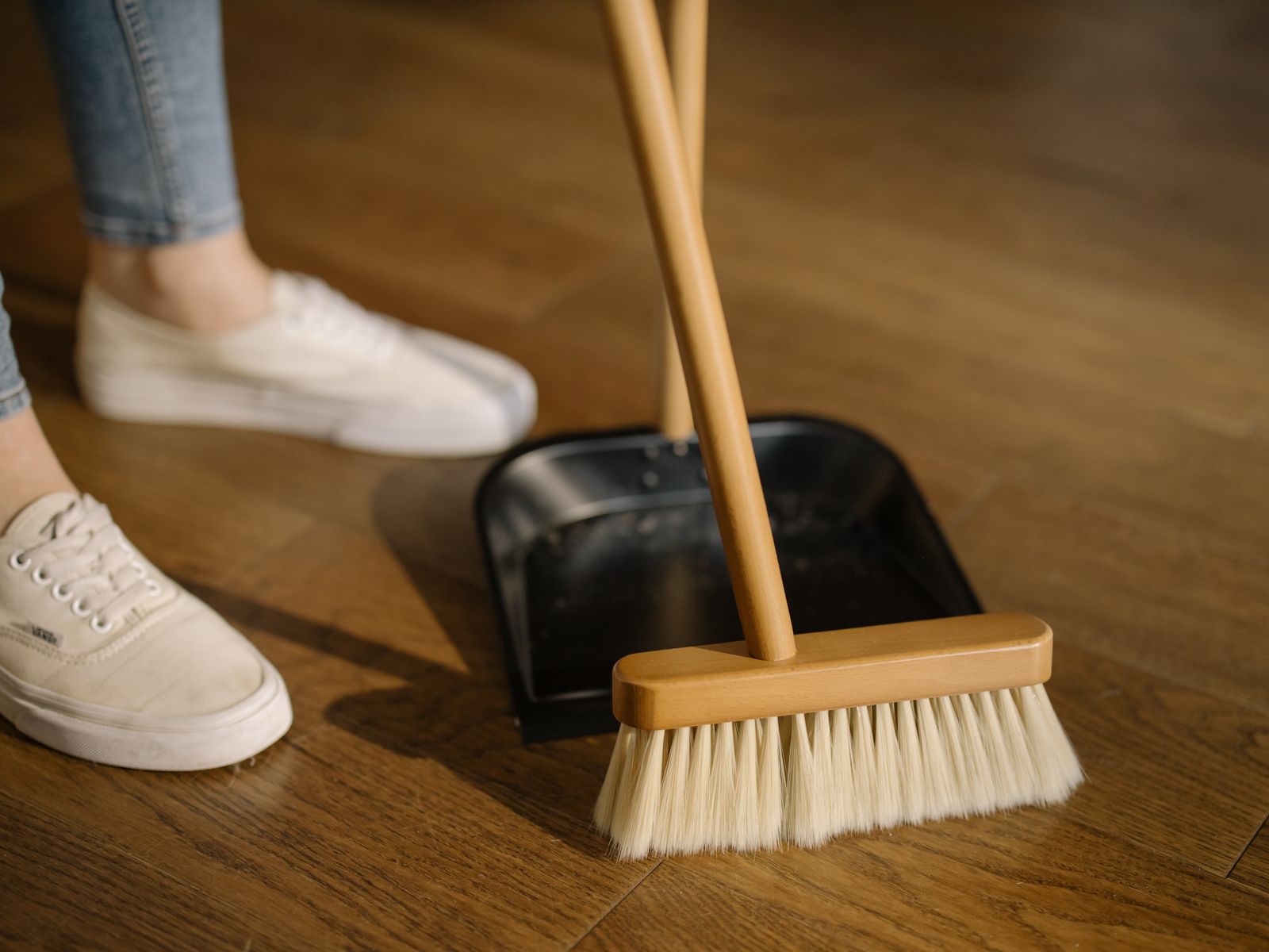 Sweeping a wooden floor with a broom and dustpan