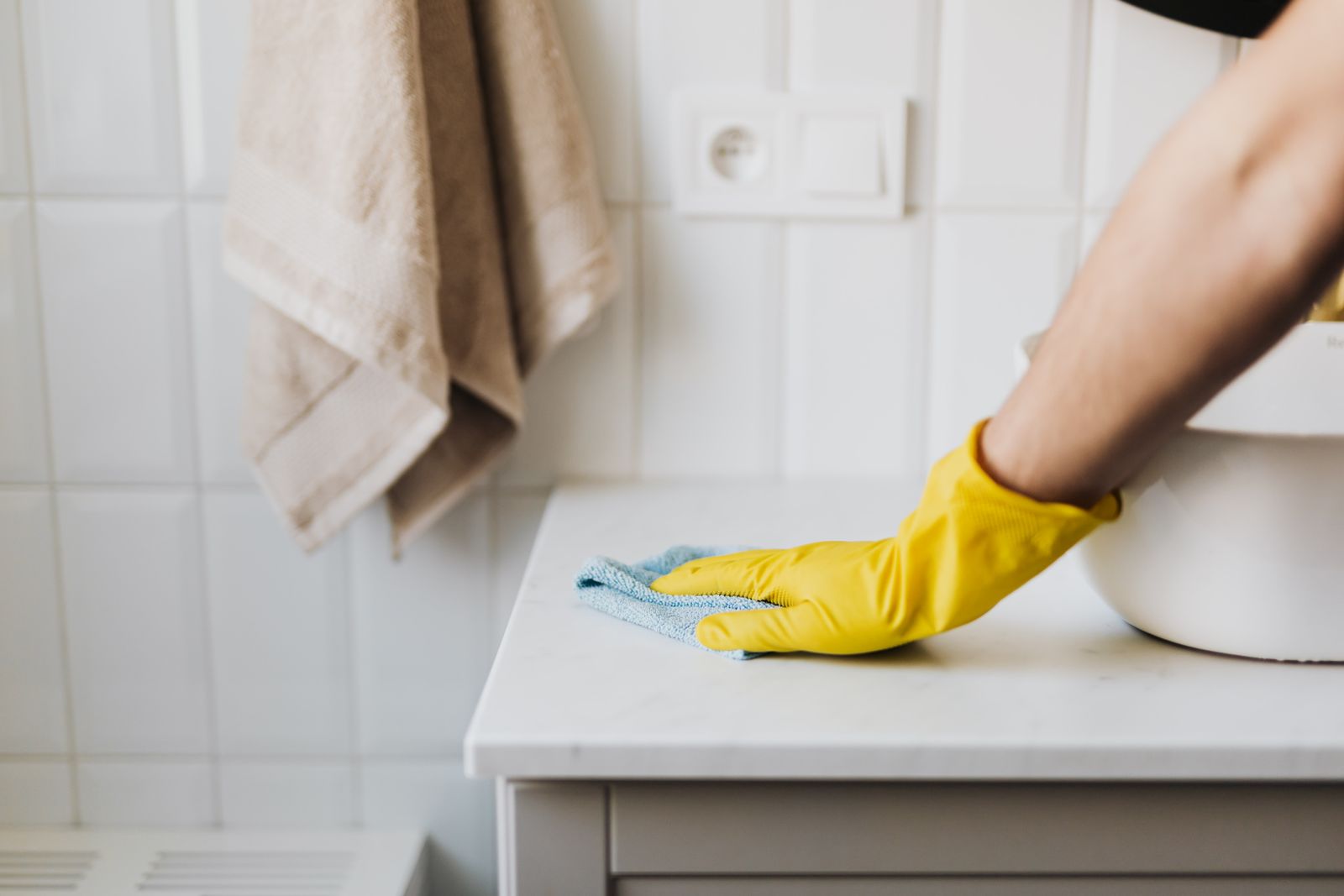 Cleaner spraying and polishing a bathroom tap until it sparkles