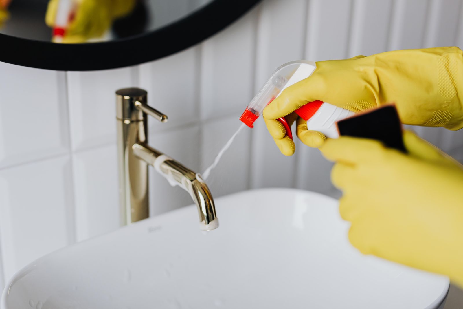 Cleaner in gloves wiping a marble worktop until it shines