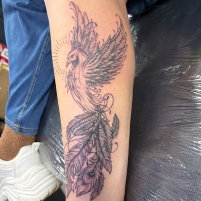 Detailed black and grey phoenix tattoo with trailing feathers on a client's forearm, tattooed at Tattoo Magic Southampton