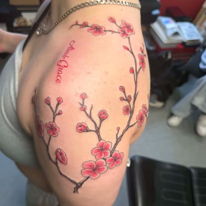 Colour cherry blossom branch tattoo with name script on shoulder and upper arm