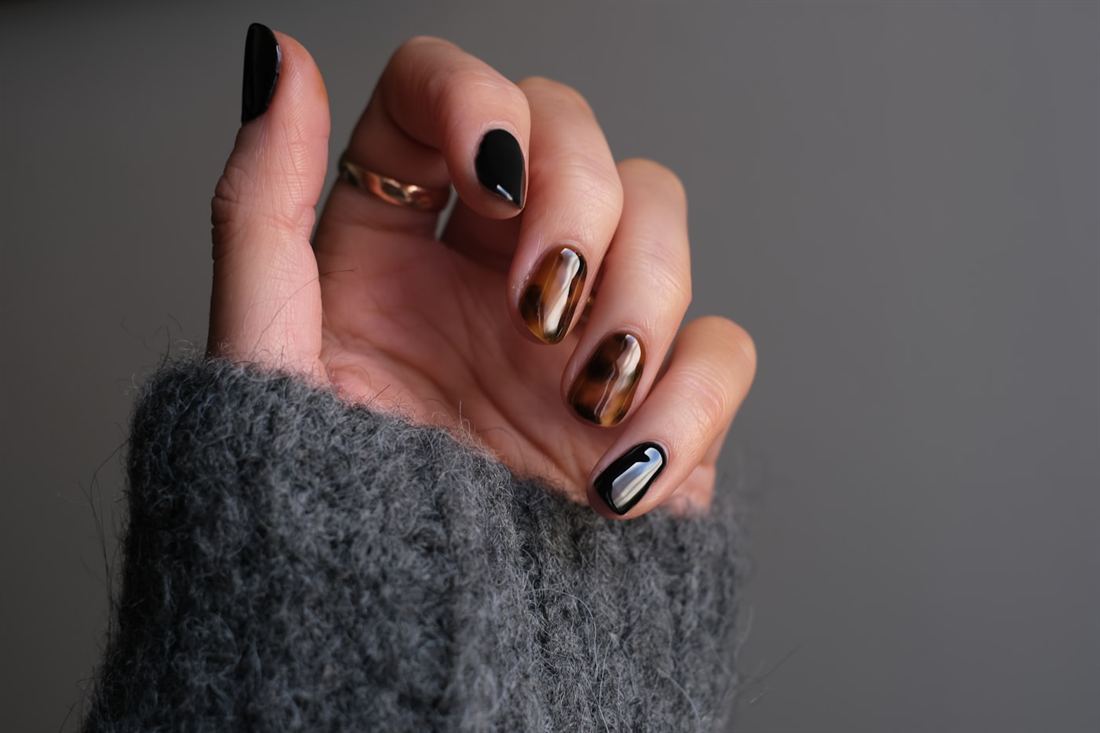 Oval gel nails in black with amber marbled nail art detail