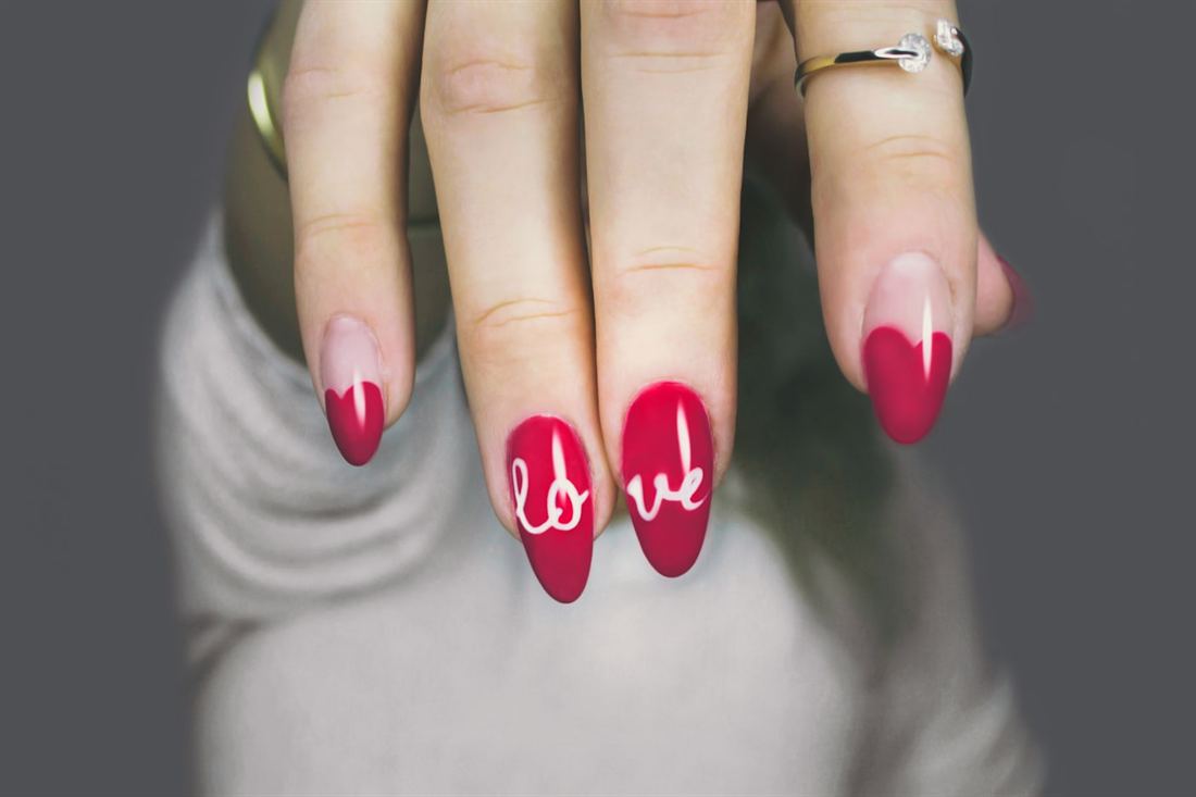 Almond gel nails in deep red with a white freehand script design