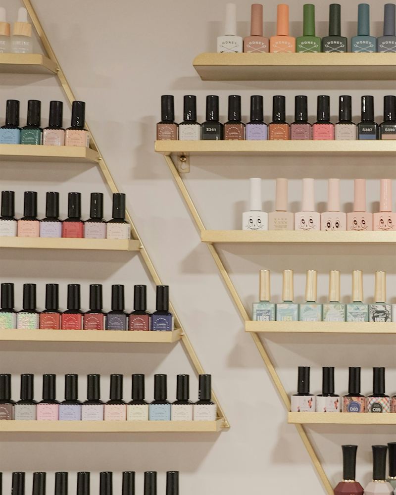 Rows of gel polish bottles in a wide range of colours displayed on salon wall shelves