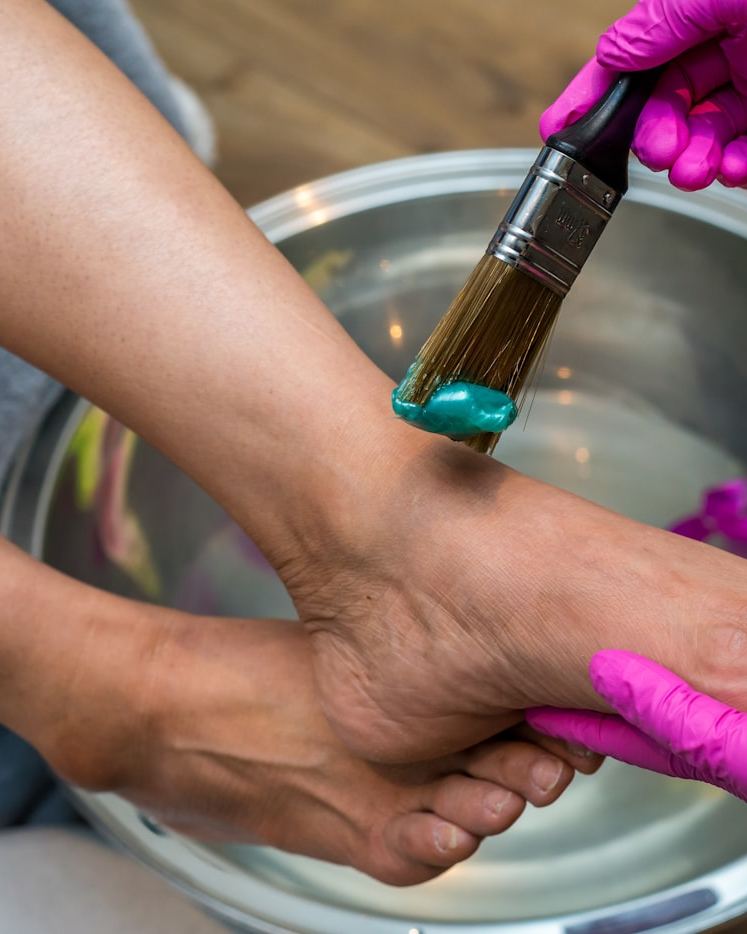 A therapist applying a warm treatment during a spa pedicure over a foot bath