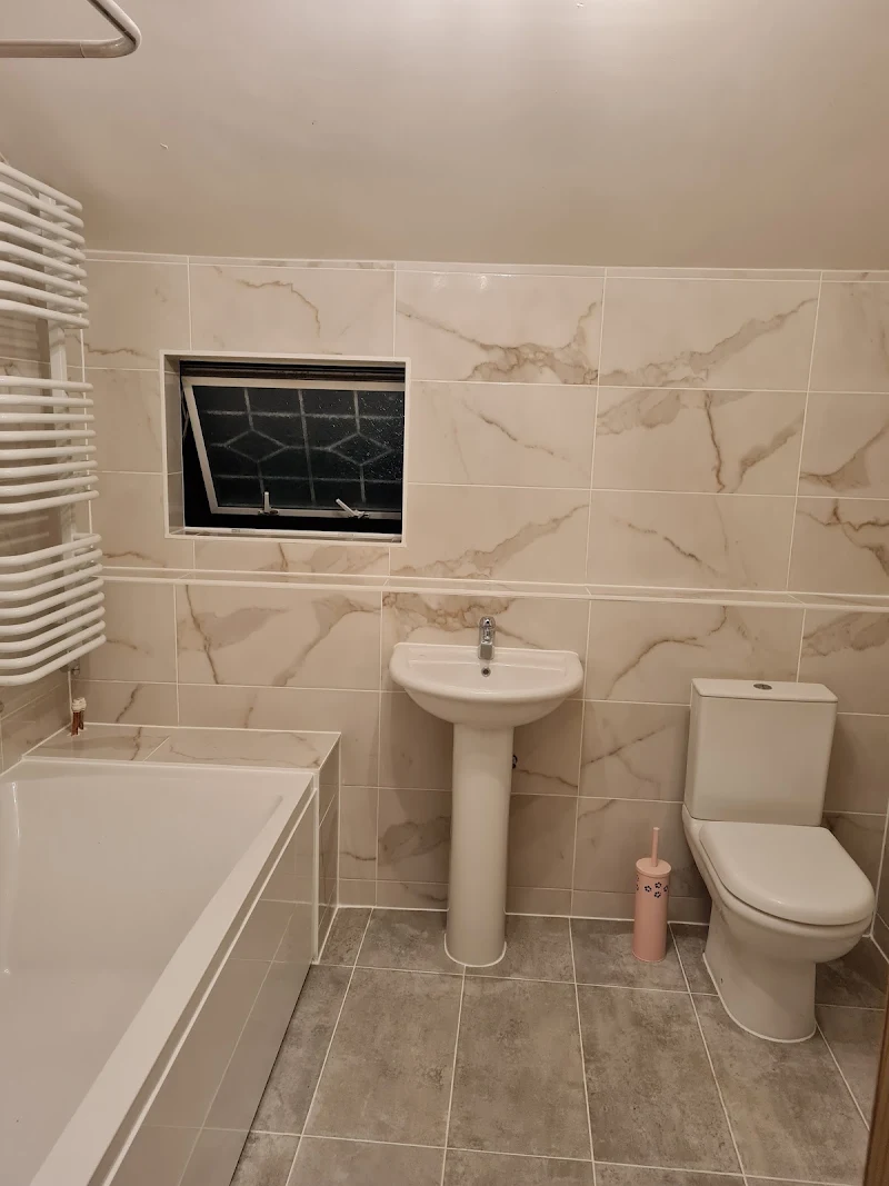 Refitted family bathroom with bath, pedestal basin and marble-effect tiling