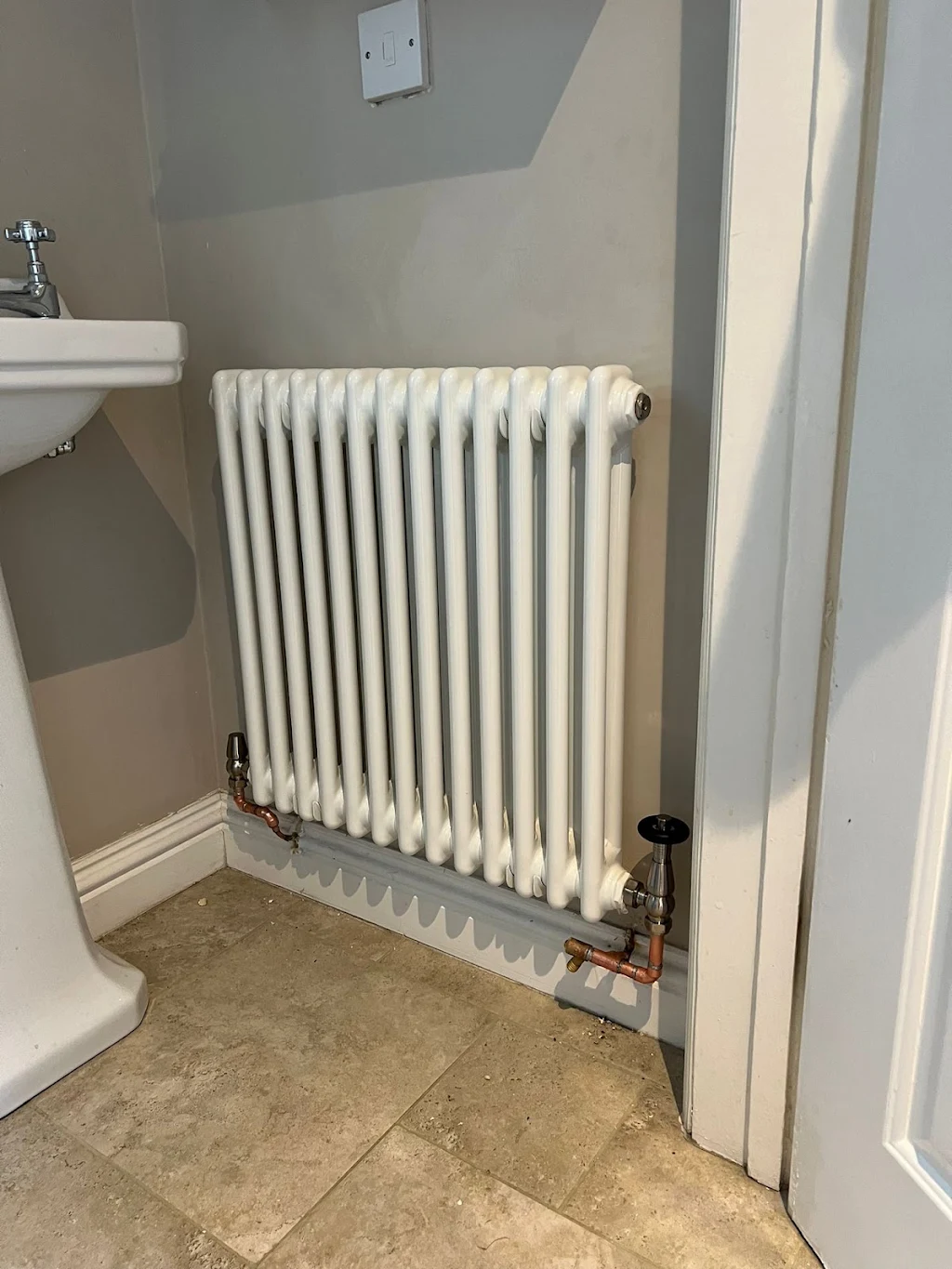 White column radiator with copper pipework installed in a bathroom