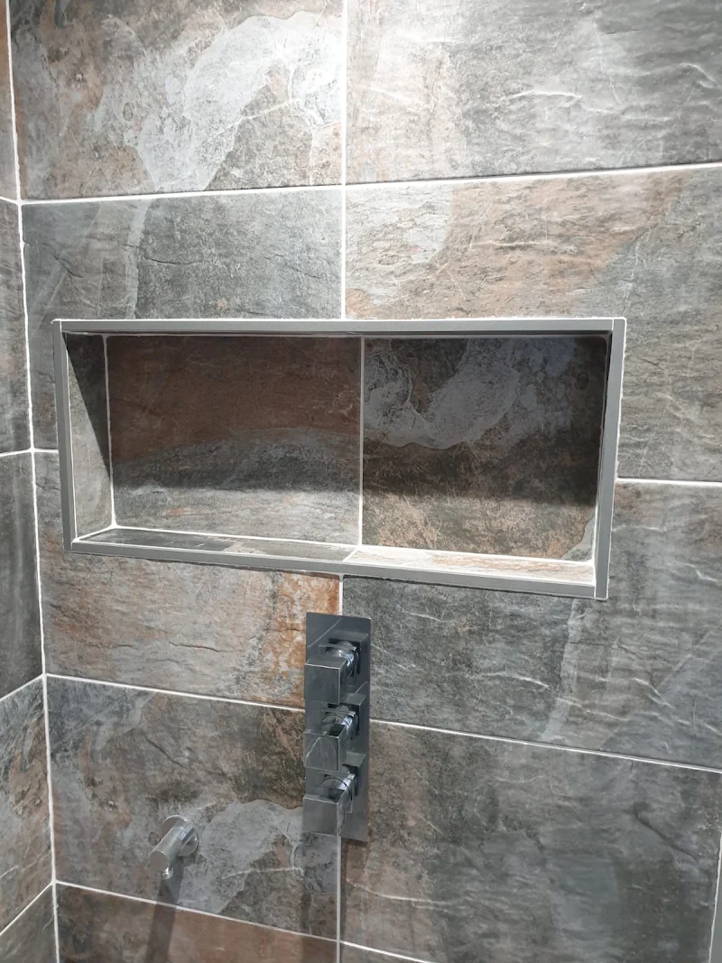 Close-up of a tiled shower niche and thermostatic shower valve