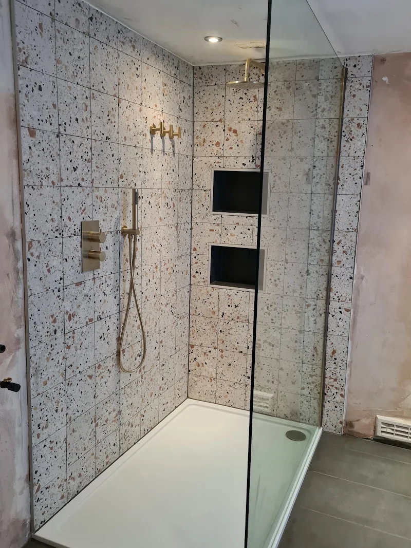 Walk-in shower with terrazzo-style tiles, brass fittings and recessed niches