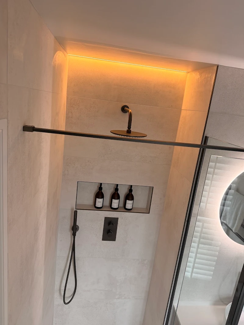 Walk-in shower with black fittings and LED-lit niche, installed by TJ Plumbing