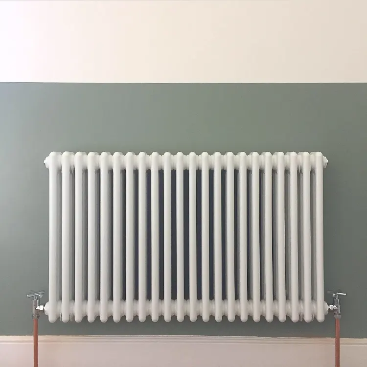 White column radiator installed on a sage green wall