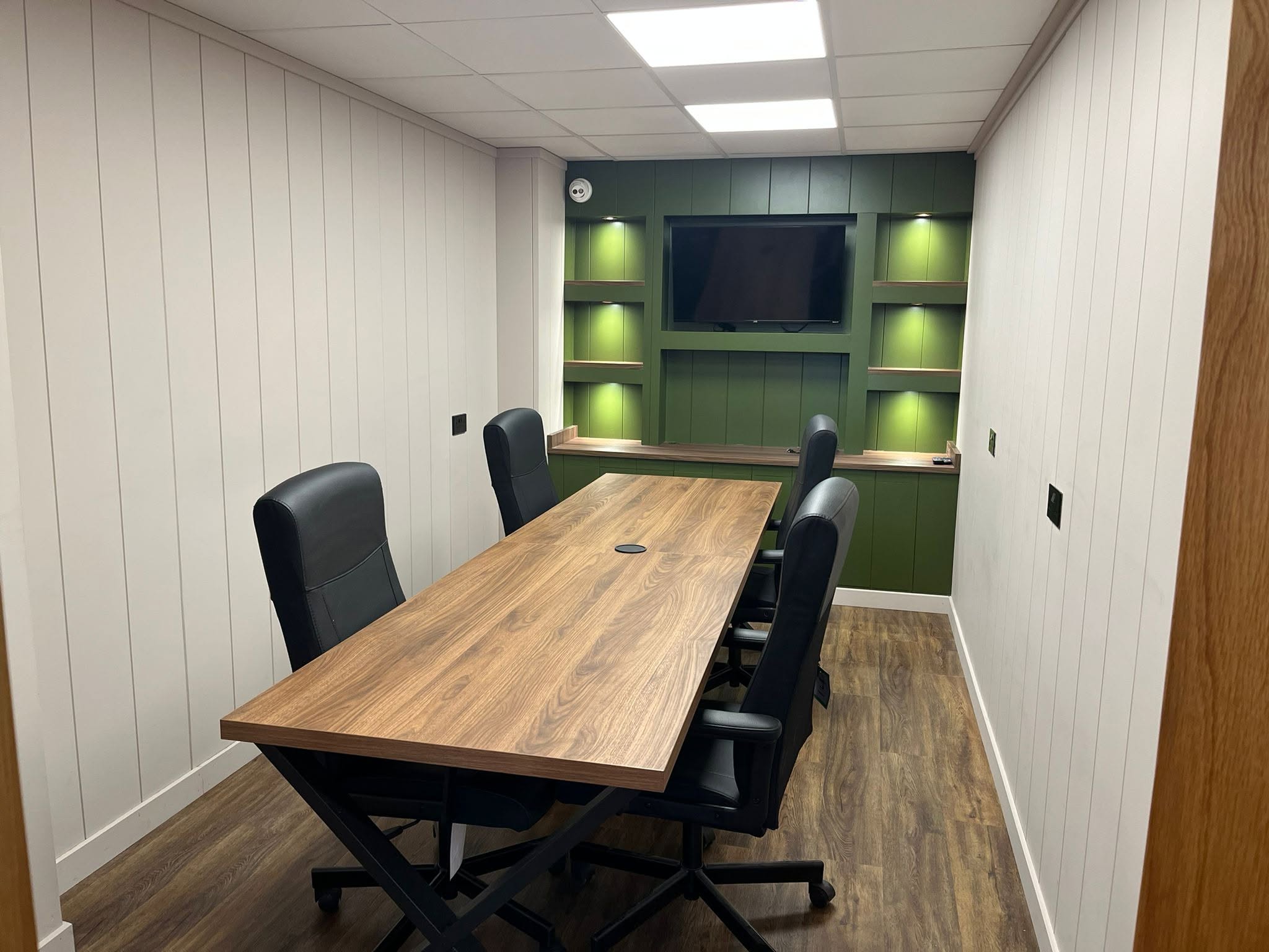 Bespoke boardroom fit-out with green panelled media wall, built by TPO Projects