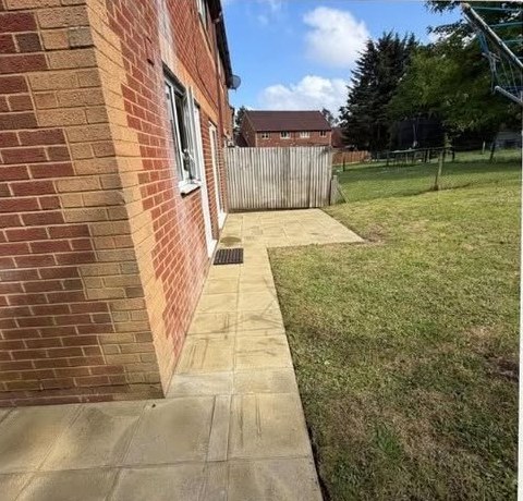 Newly laid patio pathway alongside a brick home